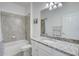 Well-lit bathroom boasts granite countertops, a shower-tub combo, and neutral gray tiling at 17732 Wayside Bnd, Punta Gorda, FL 33982