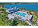 Aerial view of community pool, clubhouse, and lake with lounge chairs and palm trees at 17732 Wayside Bnd, Punta Gorda, FL 33982
