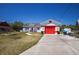Charming single-story home featuring a red garage door and accent trim, set against a clear blue sky at 1821 16Th E Ave, Bradenton, FL 34208