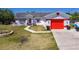 Charming single-story home featuring a red garage door and accent trim, set against a clear blue sky at 1821 16Th E Ave, Bradenton, FL 34208