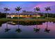 Waterfront home exterior reflecting sunset colors, framed by palm trees, creating a peaceful and luxurious setting at 18826 Ganton Ave, Lakewood Ranch, FL 34202