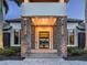Grand home entrance featuring stone pillars, contemporary lighting, and a glimpse of the elegant interior through a glass door at 18826 Ganton Ave, Lakewood Ranch, FL 34202