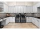 Spacious laundry room with white cabinets, granite counters, modern appliances, and stylish backsplash at 18826 Ganton Ave, Lakewood Ranch, FL 34202