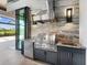 Luxury outdoor kitchen with stainless steel appliances, stone countertops, and lake views at 18826 Ganton Ave, Lakewood Ranch, FL 34202