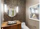Unique powder room featuring a modern sink, decorative mosaic tile wall, and round mirror with gold trim at 18826 Ganton Ave, Lakewood Ranch, FL 34202