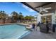 A swimming pool with outdoor lounge chairs, covered patio, and sliding doors to the home at 2647 Britannia Rd, Sarasota, FL 34231