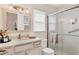 This bathroom boasts white cabinets, vanity, framed mirror, glass-enclosed shower, and tile flooring at 3449 Yonge Ave, Sarasota, FL 34235