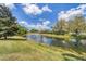 Beautiful pond view with a fountain, blue sky, and mature trees, creating a tranquil outdoor space at 3449 Yonge Ave, Sarasota, FL 34235