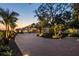 Stunning home with a paver driveway, beautiful landscaping, and lush palm trees, beautifully lit at dusk at 3931 Bay Shore Rd, Sarasota, FL 34234