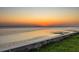 Beautiful sunset view over the water, showing a tranquil setting with a lighted seawall and soft, warm colors at 3931 Bay Shore Rd, Sarasota, FL 34234