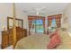 Bedroom features a four-poster bed, ceiling fan and dresser with views of the pool at 407 Fieldstone Dr, Venice, FL 34292