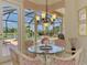Bright breakfast nook featuring a glass table, pool views and an elegant chandelier at 407 Fieldstone Dr, Venice, FL 34292