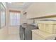 Well-lit laundry room featuring a washer, dryer, storage cabinets, and neutral decor at 407 Fieldstone Dr, Venice, FL 34292