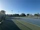 Well-maintained tennis courts under a bright sunny sky surrounded by lush greenery and fencing at 4907 Kilty E Ct, Bradenton, FL 34203