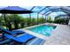 A screened in pool area features blue lounge chairs, a pool, spa, and surrounding landscaping at 4970 Oyster Pearl St, Lakewood Ranch, FL 34211