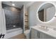 Modern bathroom with a gray tiled shower, floating shelves, and a large, illuminated round mirror at 540 S Polk Dr, Sarasota, FL 34236