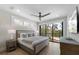 Calm bedroom with a king bed, ceiling fan, and large sliding glass doors with views of palm trees at 540 S Polk Dr, Sarasota, FL 34236