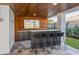 Outdoor bar area with custom wood and stone finishes, a flat screen TV, and barstool seating at 540 S Polk Dr, Sarasota, FL 34236