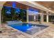 A luxurious pool and spa area illuminated by ambient lighting and showcasing a modern waterfall feature at 540 S Polk Dr, Sarasota, FL 34236
