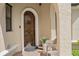 Arched wood front door with brick pavers and lush plants by a white wicker chair at 5624 Aaron Ct, Sarasota, FL 34232