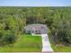 Expansive aerial view of the single-story home with a long drive and ample green space surrounded by trees at 5672 Jonesboro Ave, North Port, FL 34288
