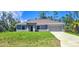 Charming single-story home with lush lawn, gray exterior, and a two car garage at 5672 Jonesboro Ave, North Port, FL 34288