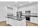 Bright kitchen features stainless steel appliances, granite countertops, white cabinets, and a center island with a sink at 5672 Jonesboro Ave, North Port, FL 34288