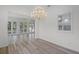 Open-concept living/dining area with wood floors, chandeliers, and French doors leading to an outdoor space at 5821 Valente Pl, Sarasota, FL 34238