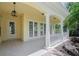 Covered porch with white columns, neutral tiling, glass doors, and an elegant lantern at 5821 Valente Pl, Sarasota, FL 34238