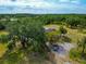 Aerial shot of a home featuring mature trees, a pool, and a paved driveway with parked car at 6321 279Th E St, Myakka City, FL 34251