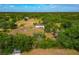 Expansive aerial view of a charming home nestled within a lush, tree-filled landscape under a partly cloudy sky at 6321 279Th E St, Myakka City, FL 34251