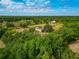 Wide aerial shot of a home with large trees and an outbuilding in the distance on a partly cloudy day at 6321 279Th E St, Myakka City, FL 34251