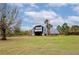 Metal barn sits on a spacious grassy lot with mature trees and a clear, sunny sky at 6321 279Th E St, Myakka City, FL 34251