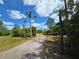Gated driveway leading to the property with lush greenery and palm trees under a beautiful blue sky at 6321 279Th E St, Myakka City, FL 34251