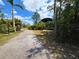 Gravel driveway framed by a metal gate and lush greenery leading to unique building at 6321 279Th E St, Myakka City, FL 34251