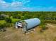 Aerial view of a metal storage building surrounded by mature trees and grassy areas at 6321 279Th E St, Myakka City, FL 34251