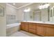Bathroom with double sinks, wood cabinets, a soaking tub, and neutral tile flooring at 6406 Grand Estuary Trl # 102, Bradenton, FL 34212