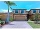 A beautiful two-story home featuring an attached two-car garage, a brick paved driveway, and lush green landscaping at 6406 Grand Estuary Trl # 102, Bradenton, FL 34212