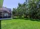Lush green backyard with a spacious lawn, mature trees, and a covered patio area, perfect for outdoor enjoyment at 6612 Butlers Crest Dr, Bradenton, FL 34203