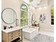 Bright bathroom features a freestanding tub, dual vanities, and a large arched window for natural light at 6612 Butlers Crest Dr, Bradenton, FL 34203