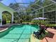 Relaxing screened-in pool area featuring a spa, patio seating, colorful plants, and an umbrella table for shade at 6612 Butlers Crest Dr, Bradenton, FL 34203
