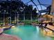 Inviting screened-in pool illuminated at night with a spa, patio seating, and lush landscaping for a peaceful retreat at 6612 Butlers Crest Dr, Bradenton, FL 34203