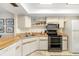 A quaint kitchen with wooden countertops, white cabinetry, and stainless steel appliances at 7201 Curtiss Ave # 2D, Sarasota, FL 34231