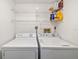 Bright laundry area with white washer and dryer and convenient overhead shelving for storage at 7201 Curtiss Ave # 2D, Sarasota, FL 34231