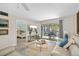 A bright living room area leads to a unit balcony and a bedroom, and includes a flat-screen television at 7201 Curtiss Ave # 2D, Sarasota, FL 34231