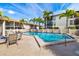Community pool area with seating; palm trees and building exteriors visible in the background under a blue sky at 7201 Curtiss Ave # 2D, Sarasota, FL 34231