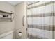 Close-up of bathroom shower featuring a shower curtain, grab bar, toilet and shelving unit at 7203 Curtiss Ave # 3D, Sarasota, FL 34231