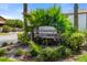 An entrance sign for 'The Crossings' with addresses, surrounded by lush landscaping at 7203 Curtiss Ave # 3D, Sarasota, FL 34231