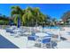 Community pool deck with white fence, tables, blue umbrellas, and palm trees at 75 Inlets Blvd # 75, Nokomis, FL 34275
