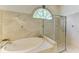 Luxurious bathroom featuring a soaking tub, glass-enclosed shower, and marble tile, creating a spa-like retreat at 7574 Camden Harbour Dr, Bradenton, FL 34212